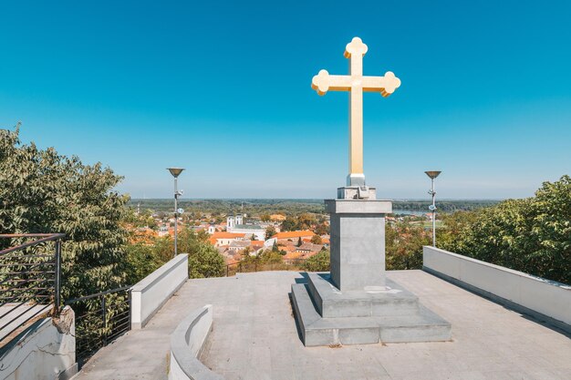 Fotografie pohled na náboženský kříž nad městem sremski karlovci, který ukazuje jeho okouzlující architekturu, historické budovy a prominentní katedrálu, srbsko