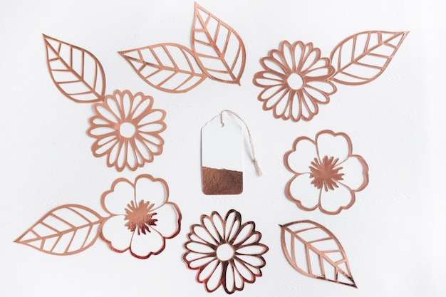 Foto grátis cortar as flores douradas e folhas com tag no centro sobre fundo branco