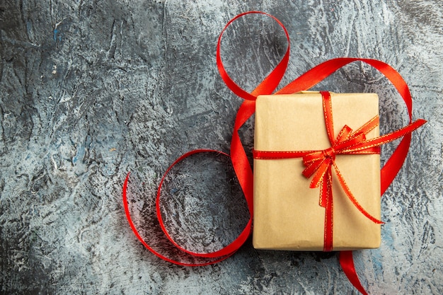 Kostenlose Foto draufsicht kleines geschenk mit rotem band auf dunklem isoliertem hintergrund gebunden