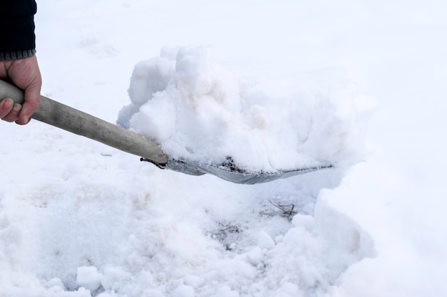 Foto ein mann reinigt schnee mit einer metallschaufel