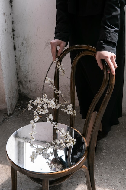 Gratis Foto ung kvinde, der poserer med spejl på stol og blomst
