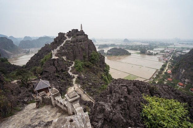 Photo landscape with mountain pagoda at bich dong with flooded rice fields and cloudy sky